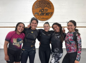 Five female black belts at 10th Planet Oakland sign