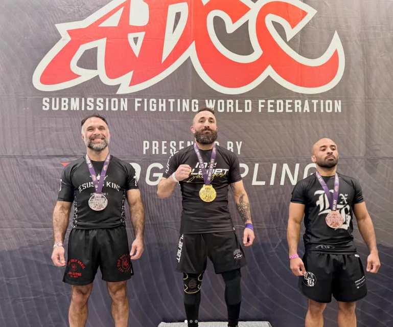Brian “Pirate” Wilkinson wearing a gold medal between the silver and bronze medalists at the ADCC Los Angeles Open