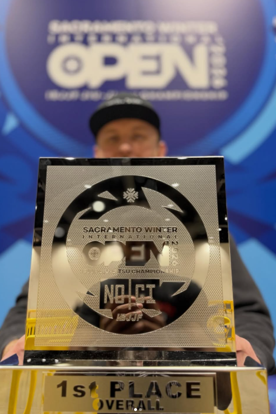Competitor holding the Sacramento Winter International Open No-Gi trophy marked “1st Place Overall”