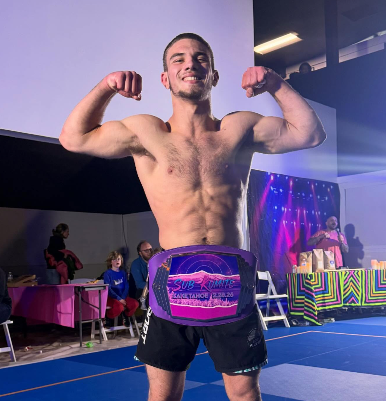Jonny Mezheritskiy smiling and flexing with the purple Sub Kumite championship belt around his waist